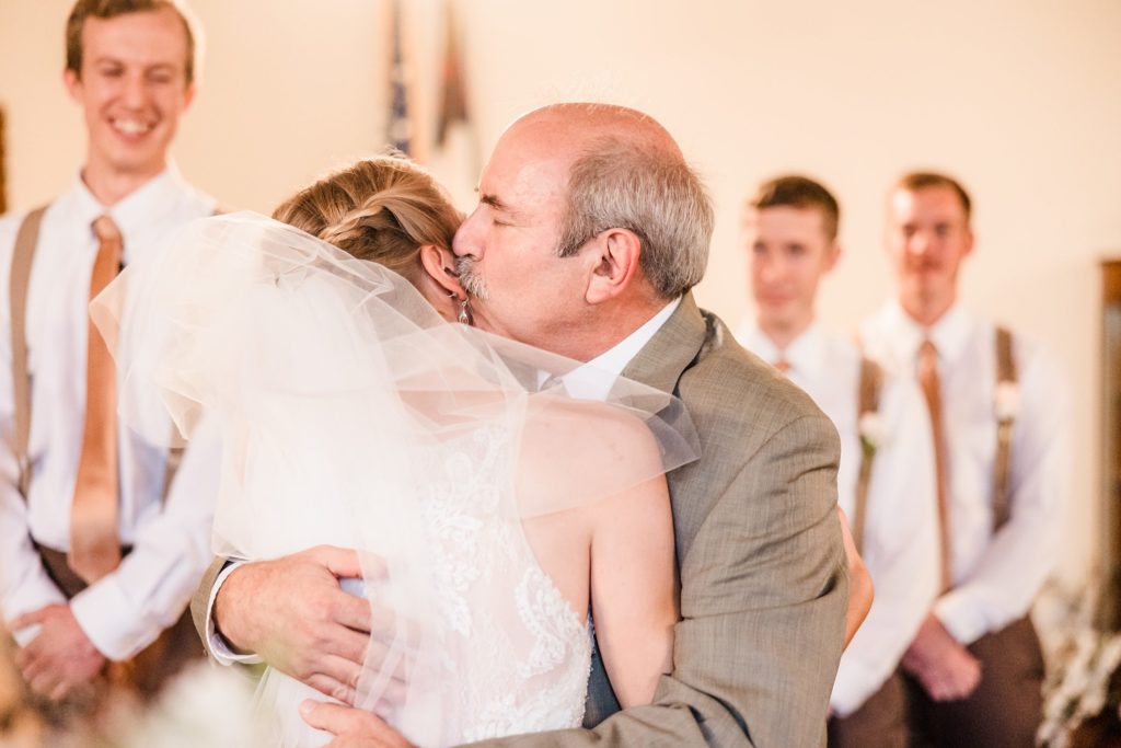 Bride's father embraces his daughter during her wedding ceremony at the Fork of Cheat Baptist Church in Morgantown, West Virginia.  Photo by Austin Wedding Photographers, Joanna & Brett