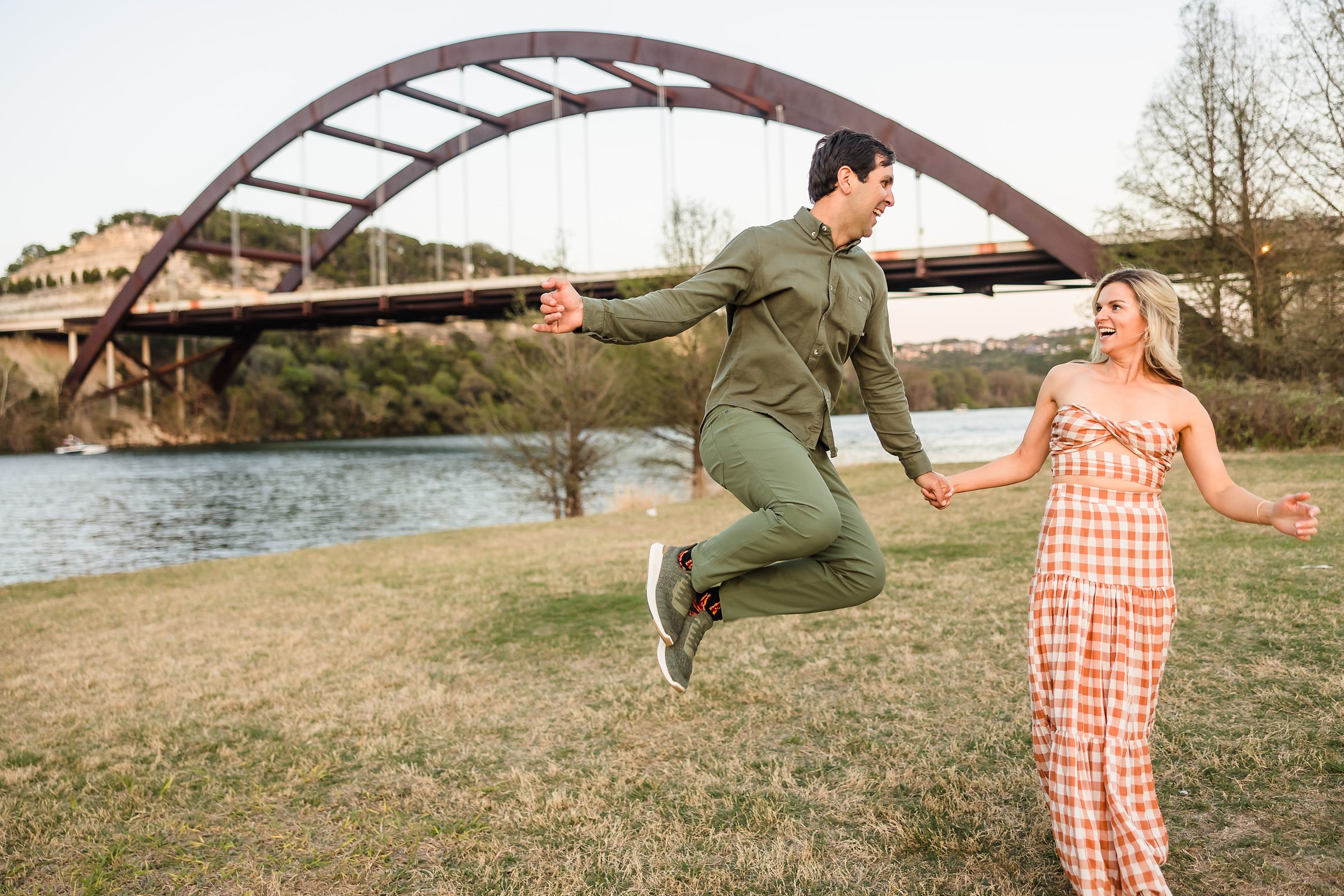Couple jump together during their engagement session at the 360 Bridge in Austin, Texas.