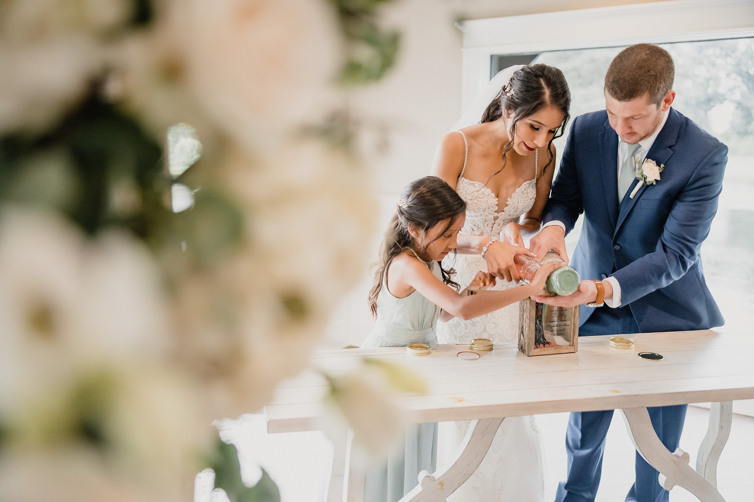 Groom, bride, and her daughter pour unity sand together during a wedding at the Fisherman's Inn in Elburn, Illinois.