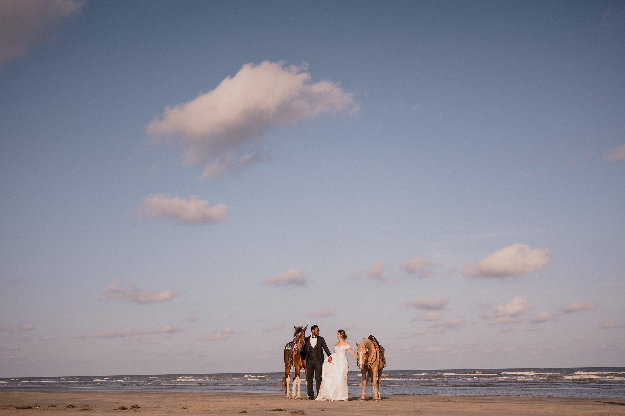 Bride and Groom Embrace with their horses during an elopement in Galveston Beach, Texas