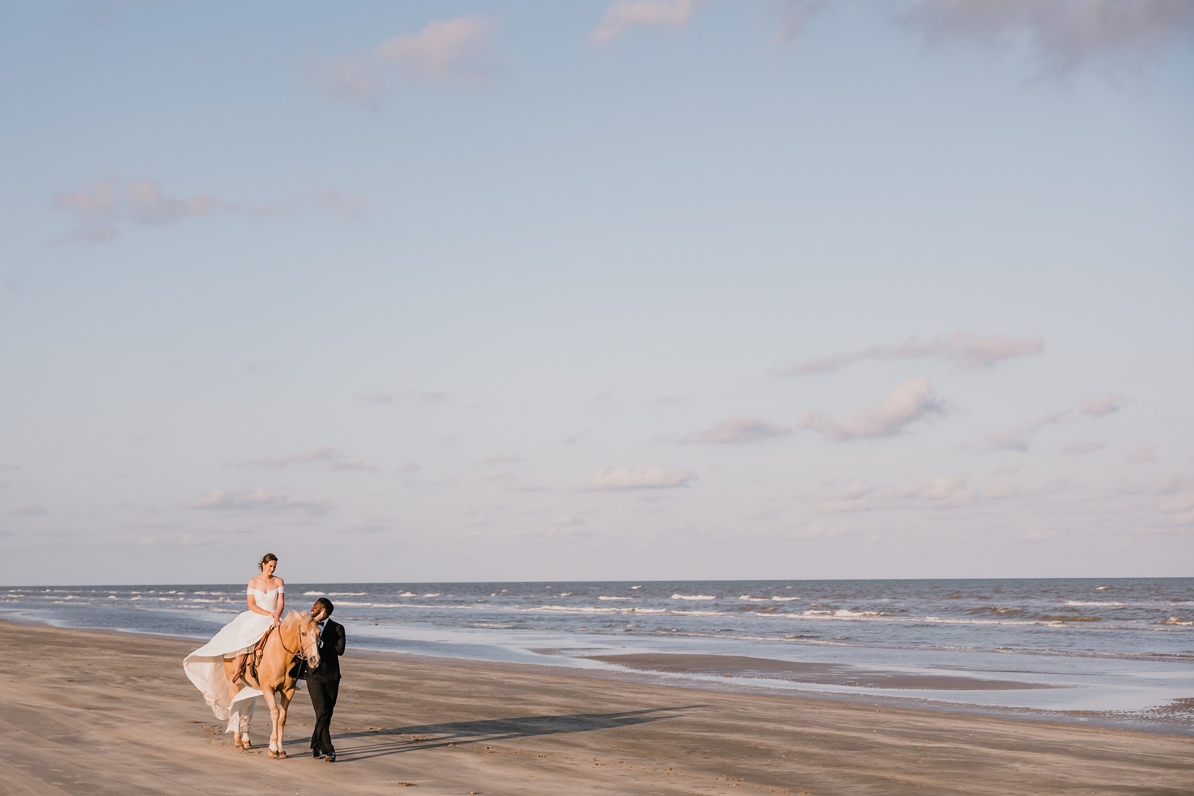 Groom and Bride walk down the beach during an elopement at Galveston Beach in Texas.