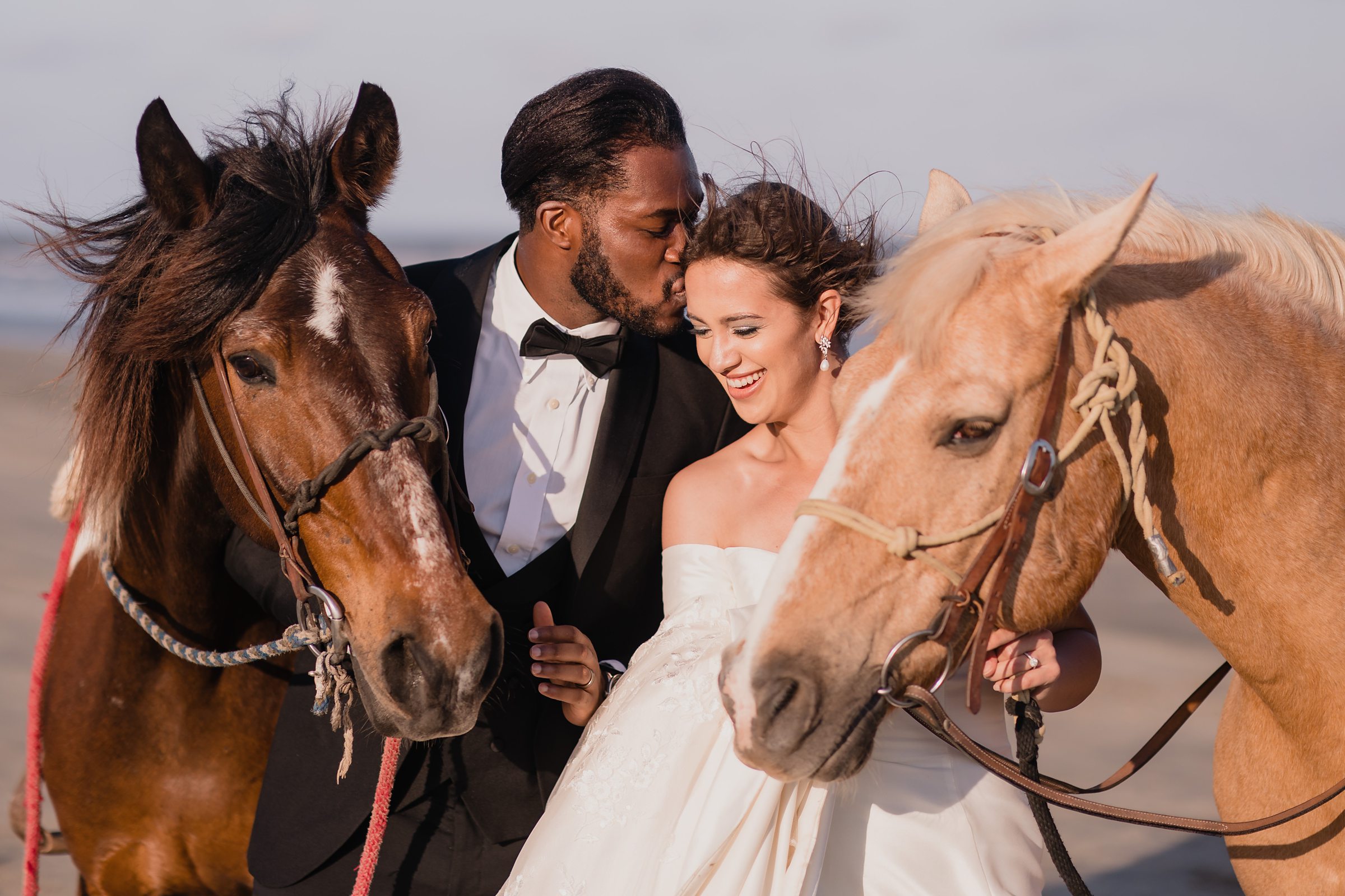 Bride and Groom Embrace with their horses during an elopement in Galveston Beach, Texas