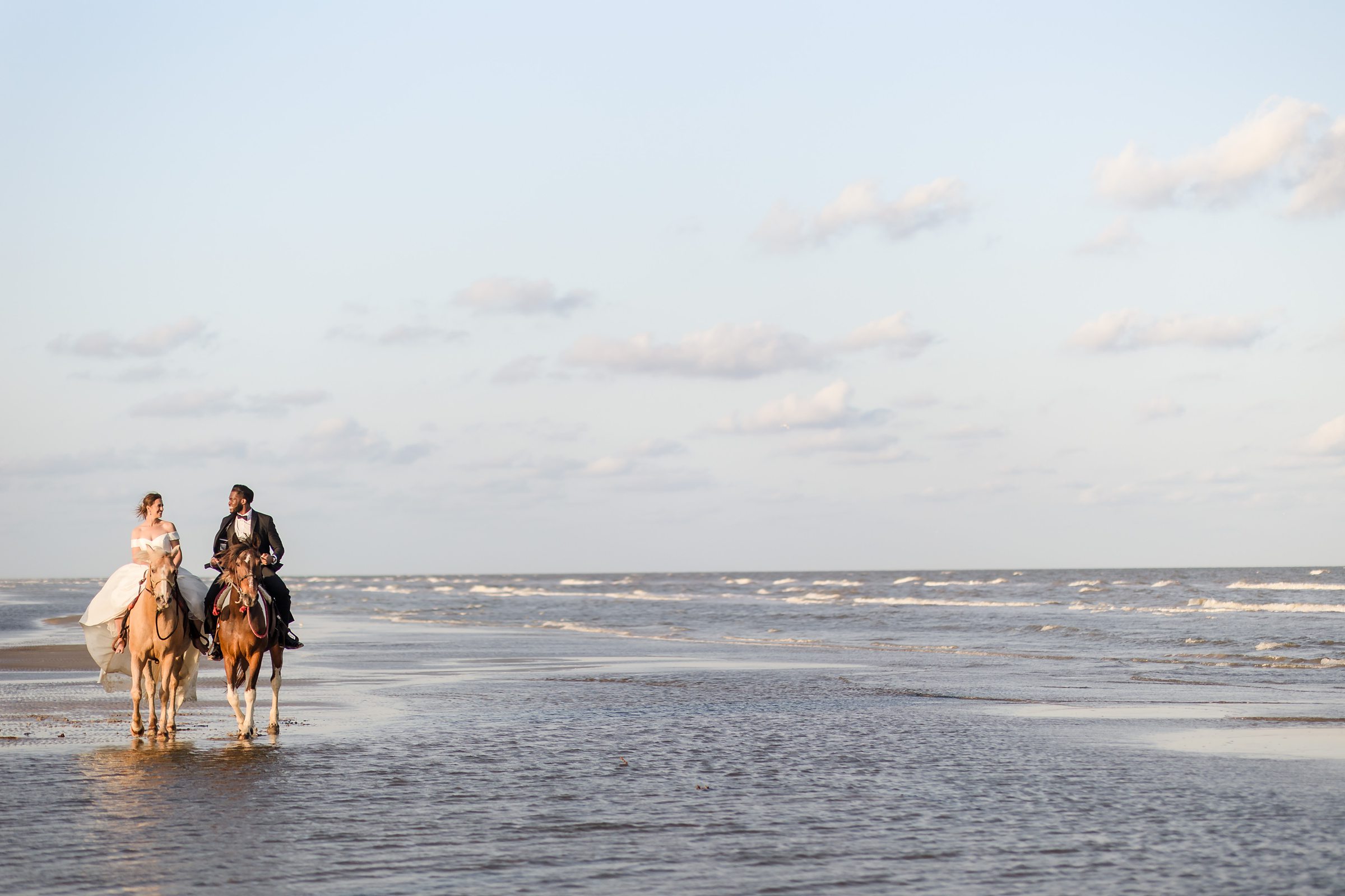 Bride and groom ride horses in the ocean during an elopement at Galveston Beach in Texas
