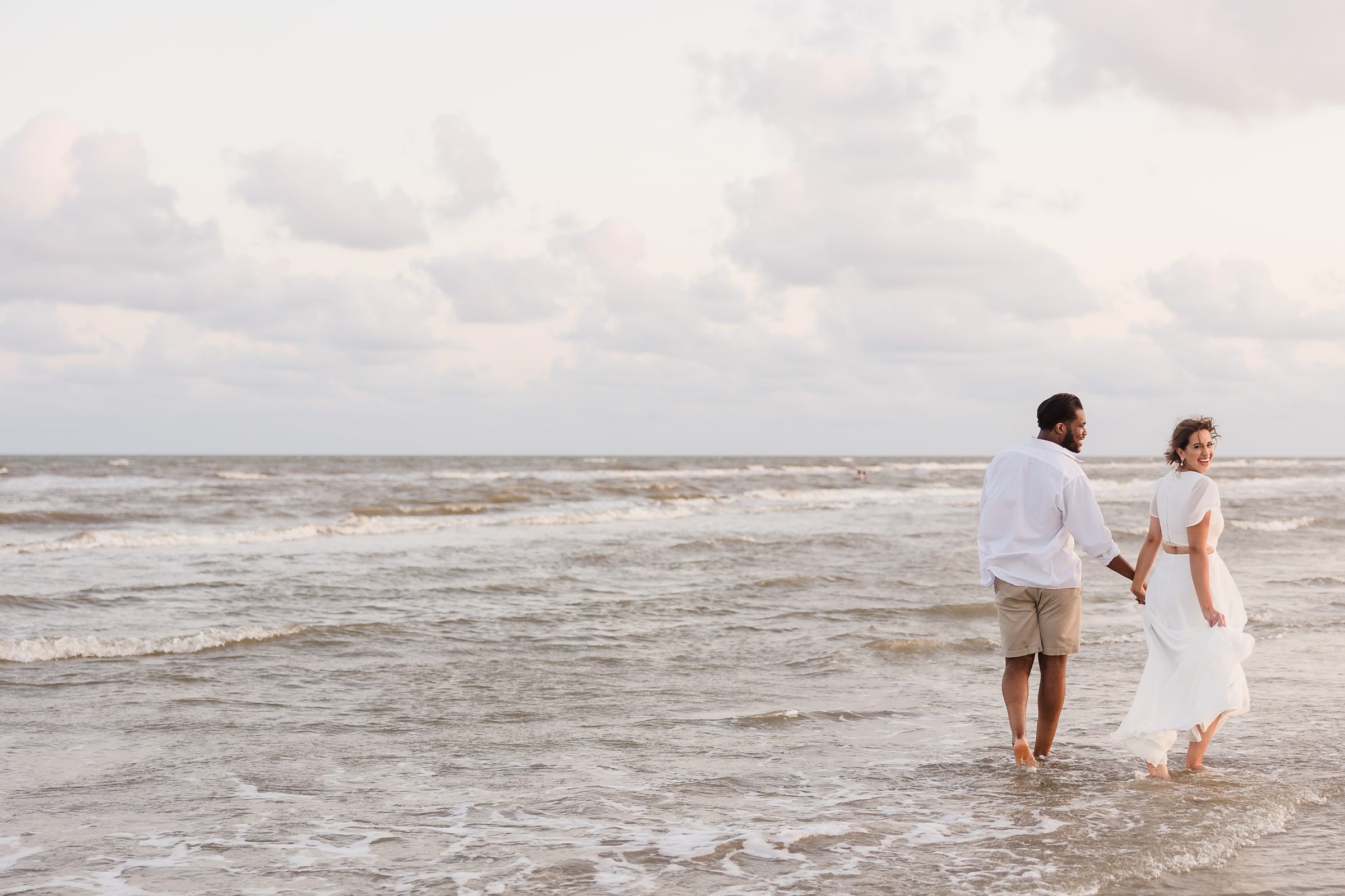 Couple walk together during their session at Galveston Beach in Texas.