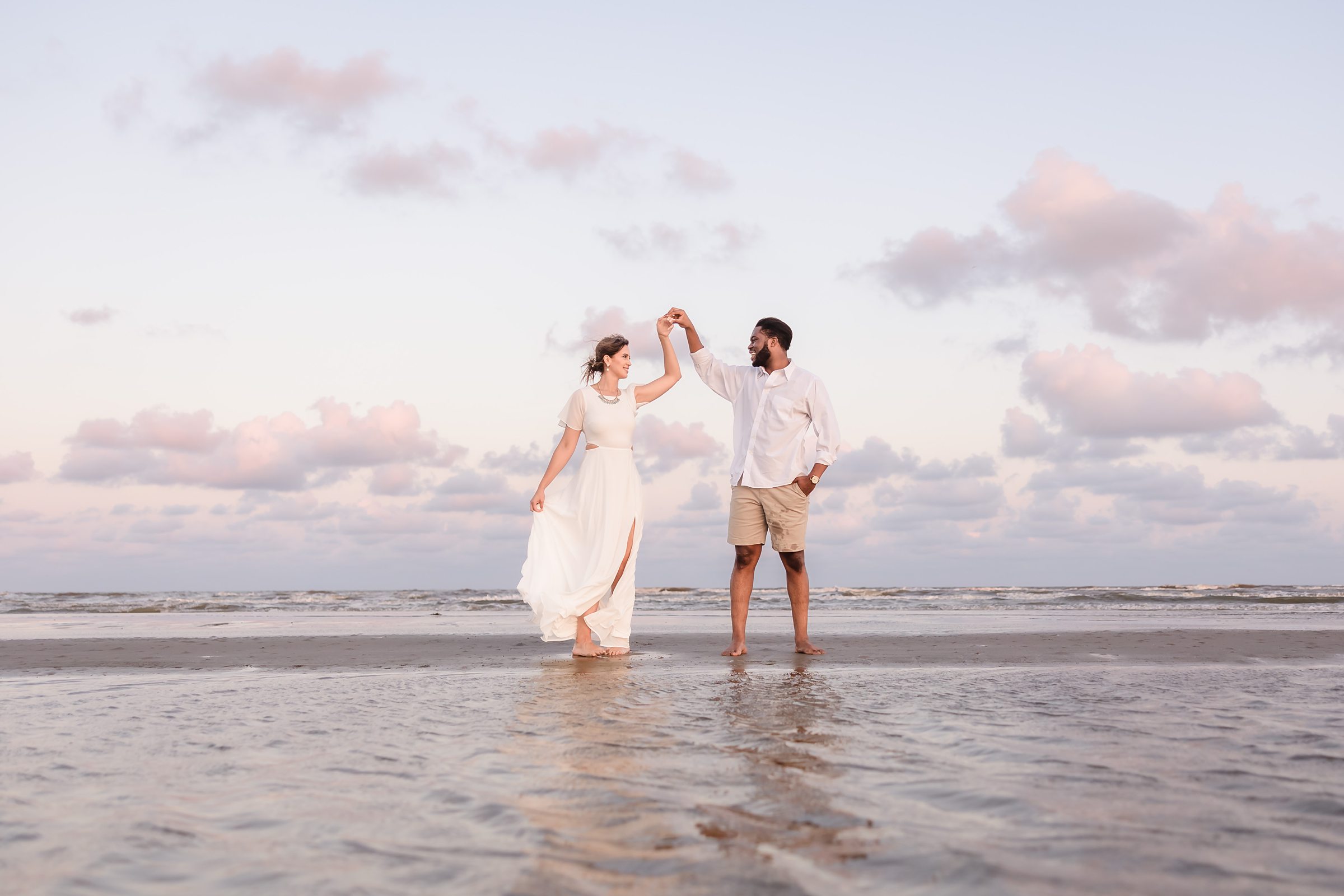 Couple twirl in the ocean during their session at Galveston Beach in Texas.