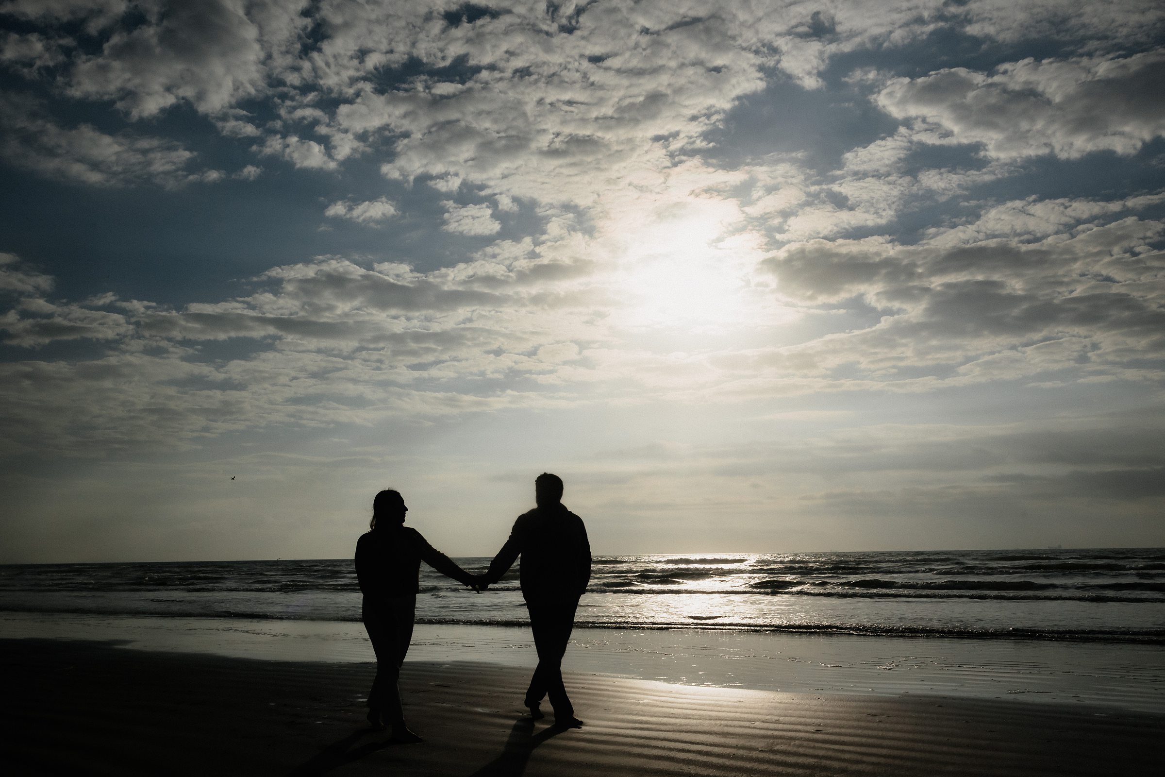 Couple walk on the beach during their Galveston Beach engagement session.