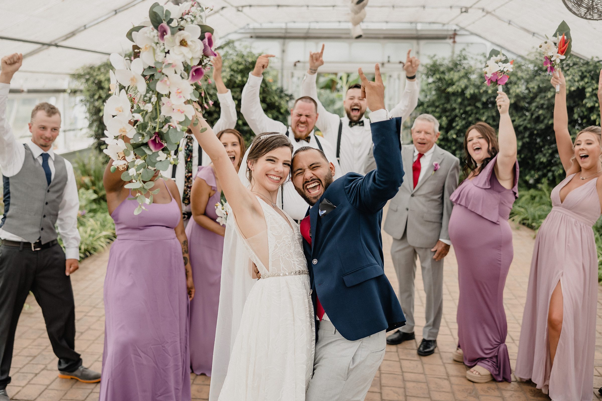 Bride and groom celebrate with their bridal party during their wedding at the Bird Haven Greenhouse & Conservatory in Joliet, Illinois.