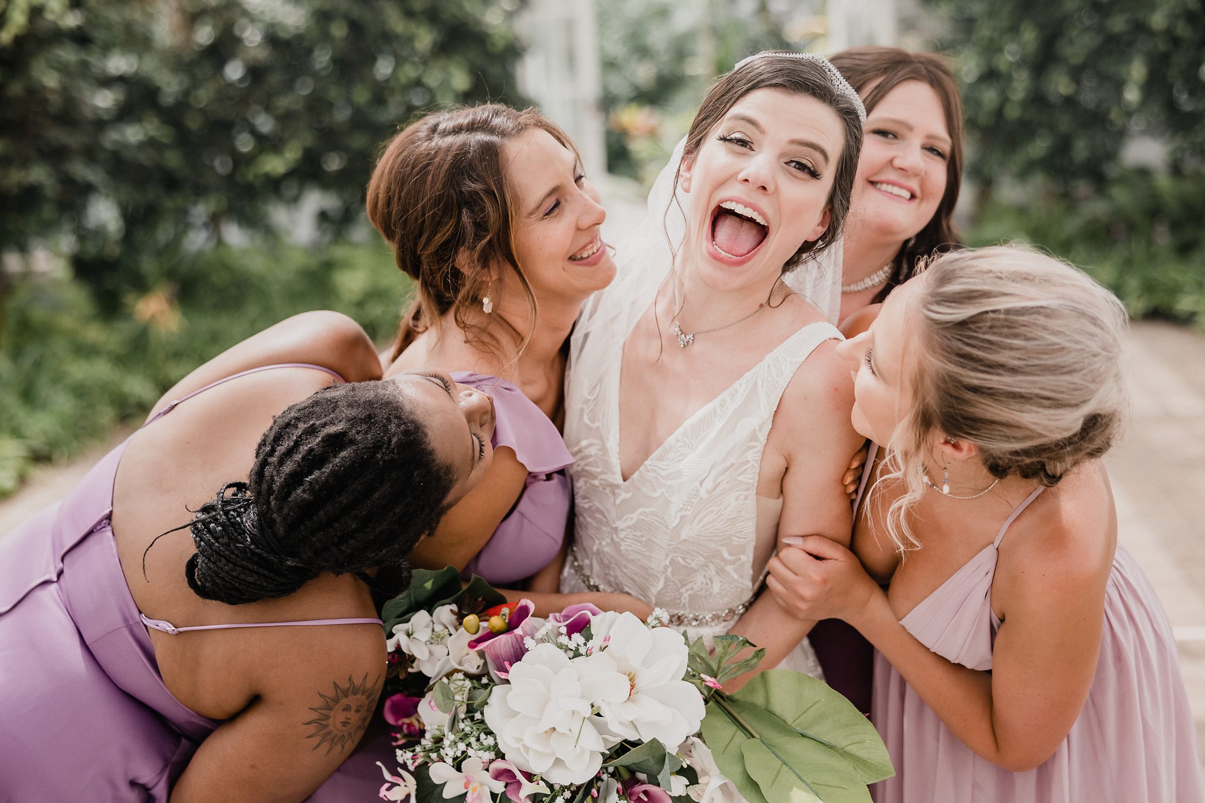 Bridesmaids hug the bride during a wedding at the Bird Haven Greenhouse & Conservatory in Joliet, Illinois.