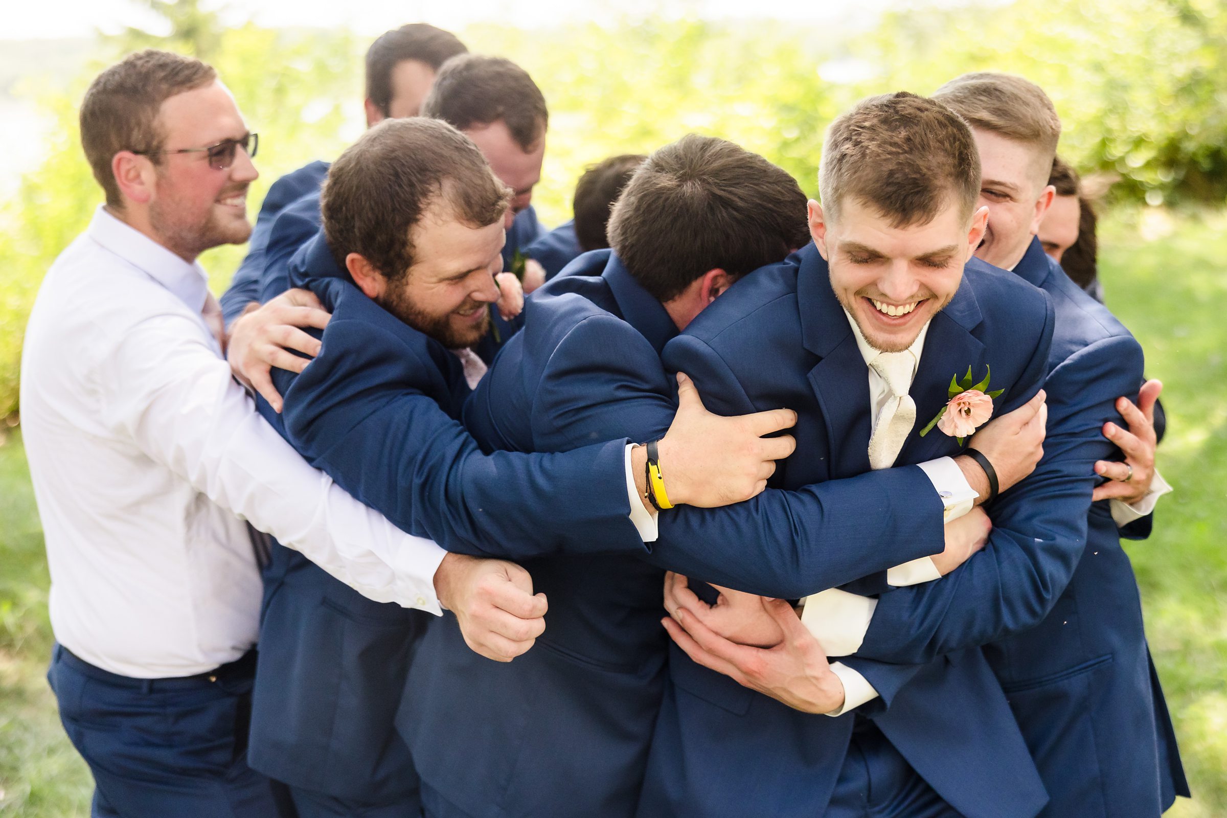 Groomsmen hug groom during his wedding at the Luthy Botanical Garden in Peoria, Illinois