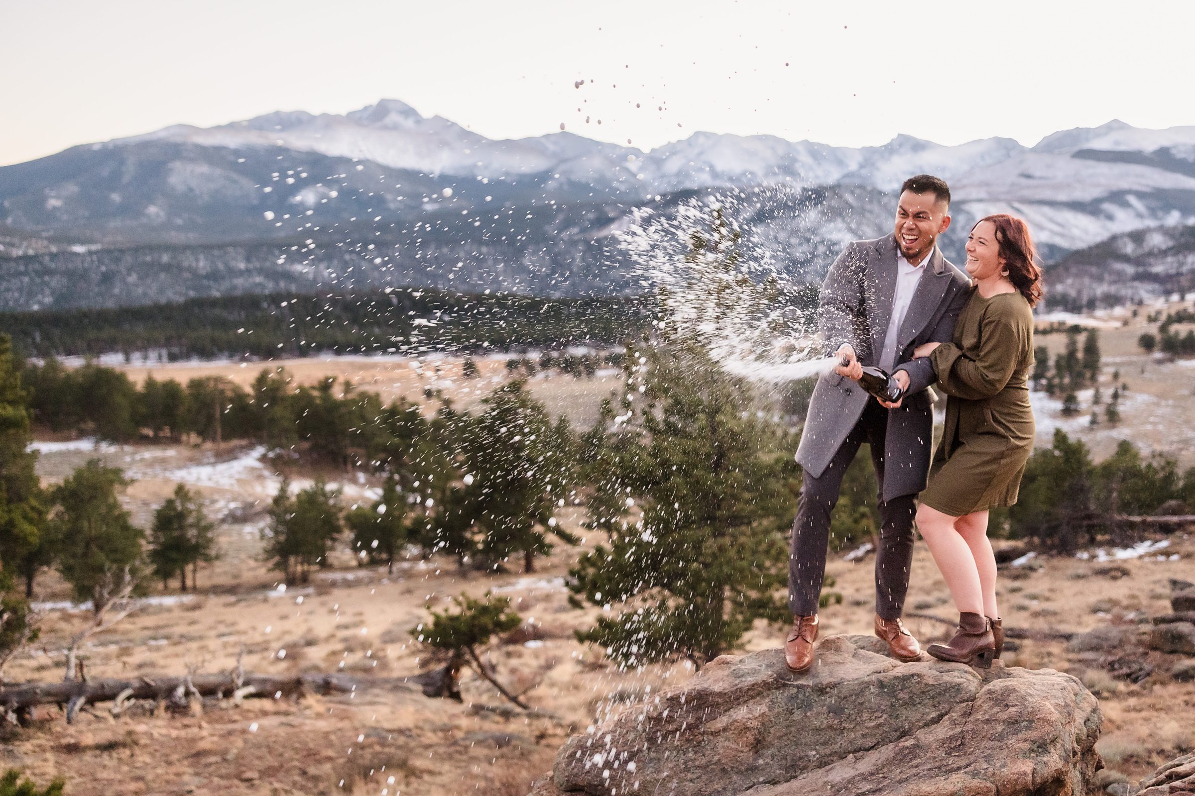Couple spray champagne during their Rocky Mountain National Park Engagement session