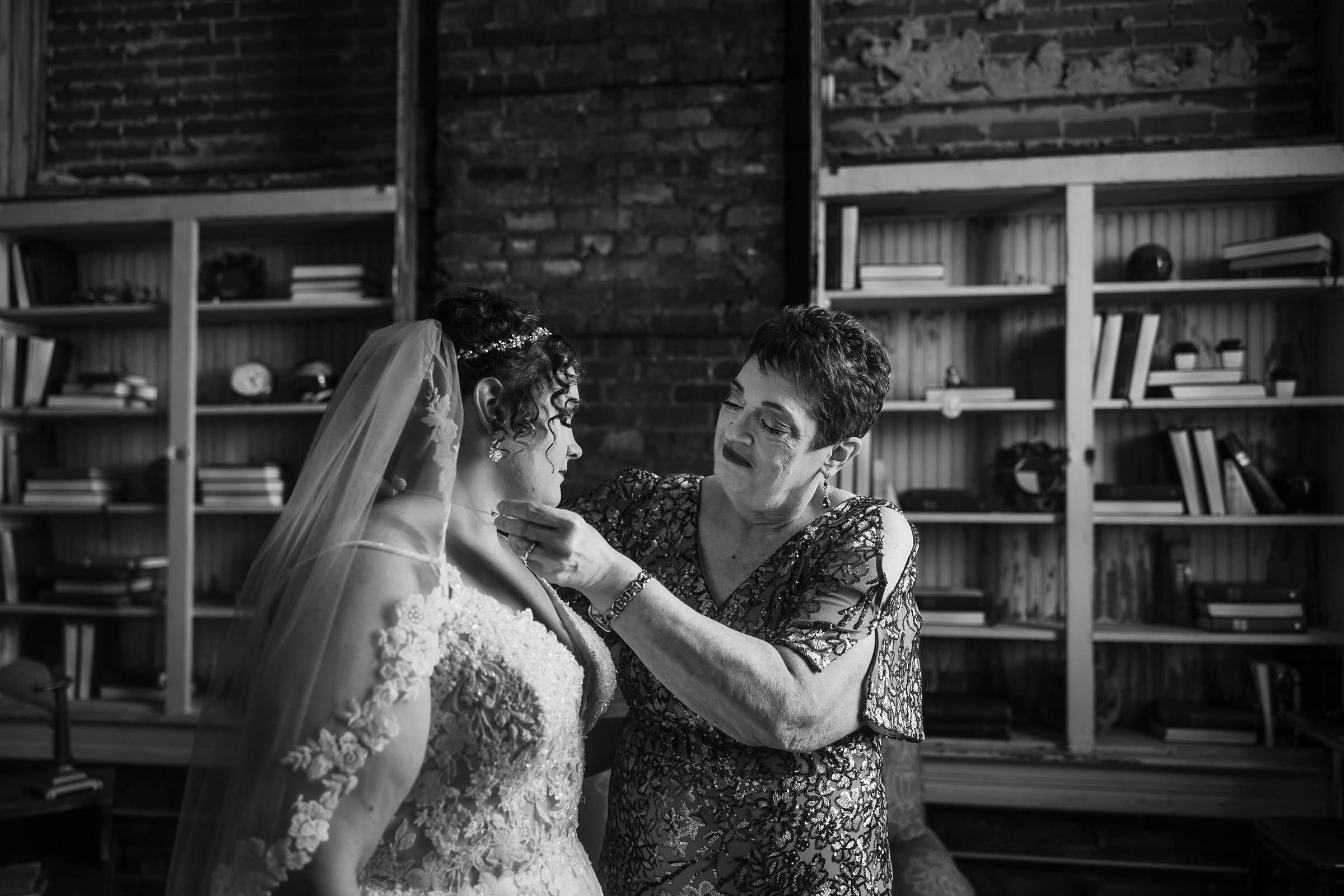 Mother helps the bride put on her necklace before her wedding at the Legacy Building in El Paso, Illinois.