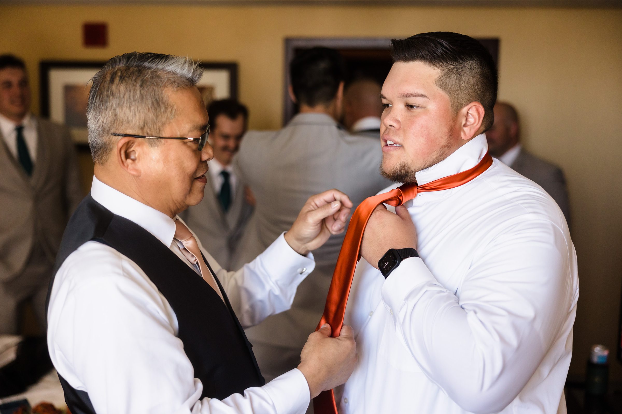 Father helps his son get ready before his wedding at the Destihl Brewery in Normal, Illinois.