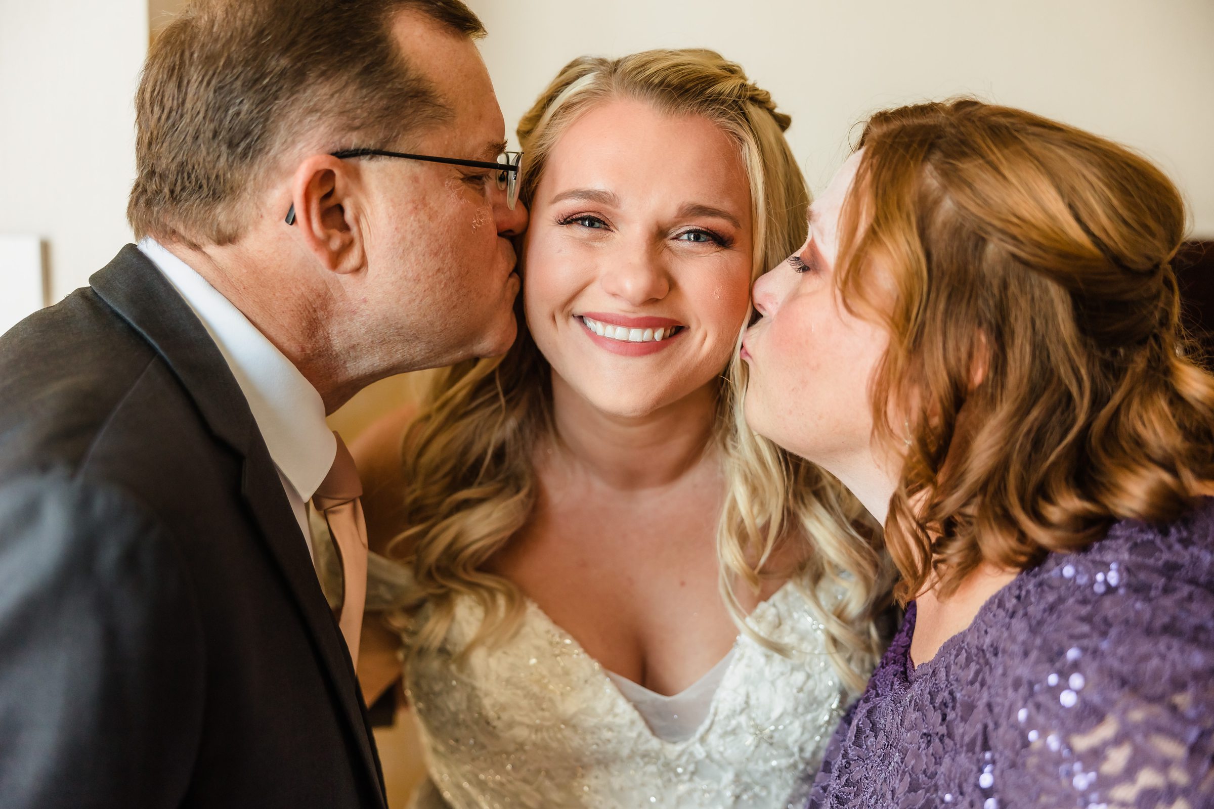Mom and dad kiss the bride before her wedding at the Destihl Brewery in Normal, Illinois.