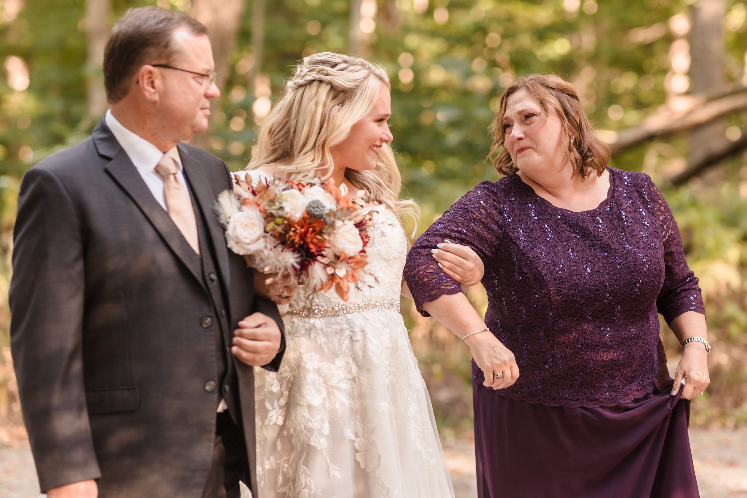 Mom and dad walk the bride down the aisle during a wedding ceremony at Funks Grove in Mclean, Illinois.