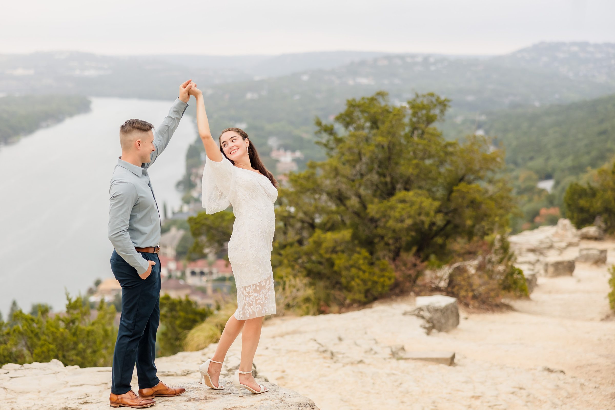 Couple twirl together during their engagement session at Mount Bonnell in Austin, Texas.