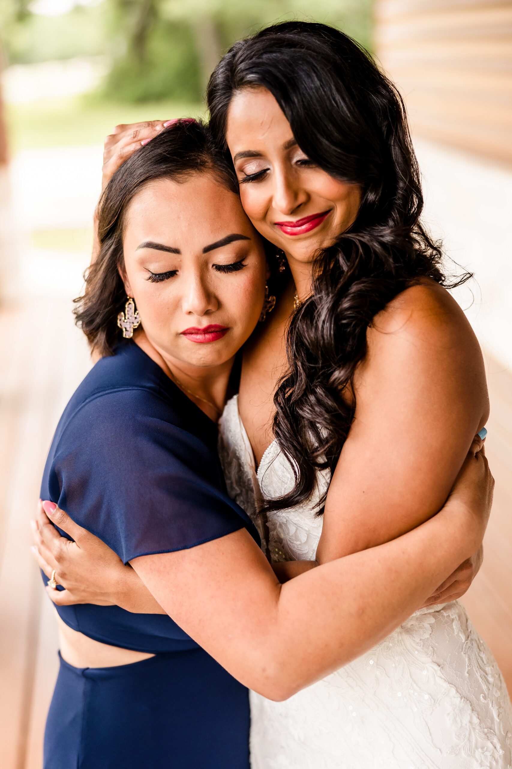 Bridesmaid and Bride hug during a wedding at the Shiraz Garden in Bastrop, Texas.