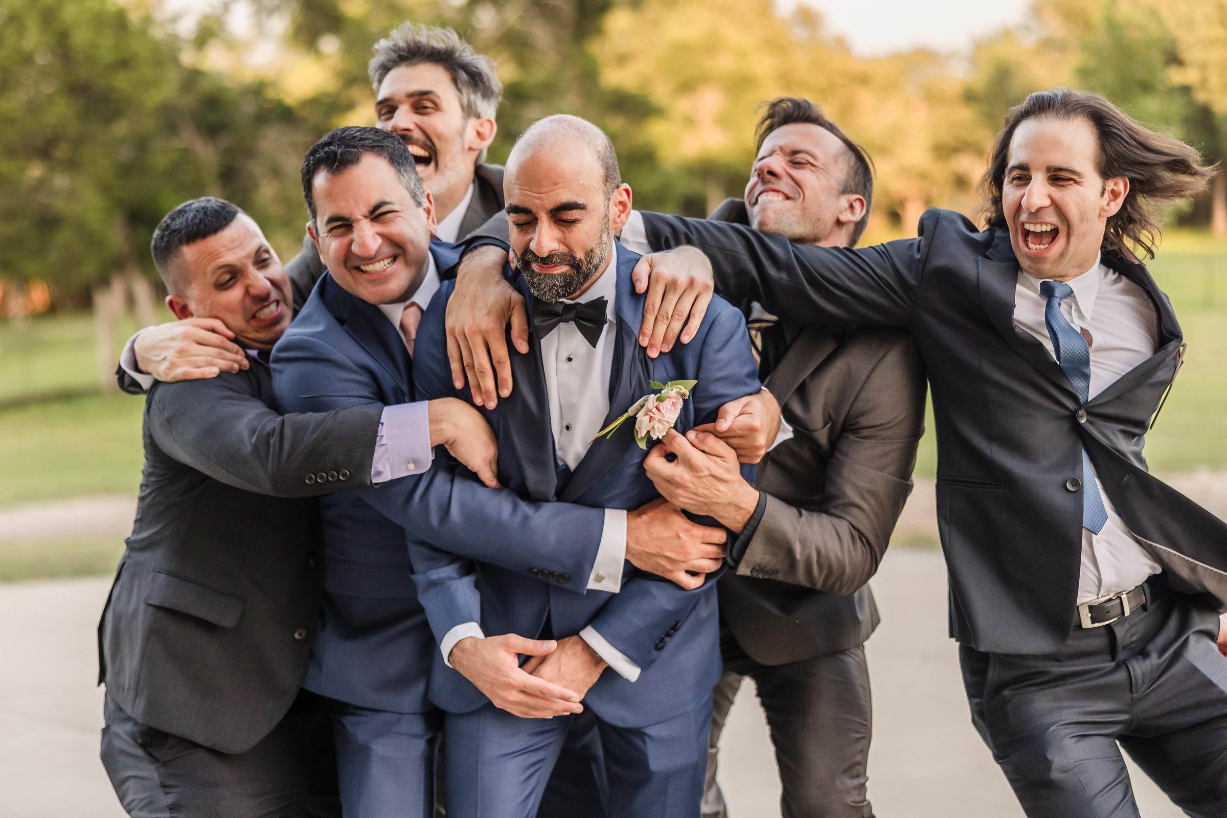 Groom gets tackled by groomsmen during a wedding at Shiraz Garden in Bastrop, Texas.